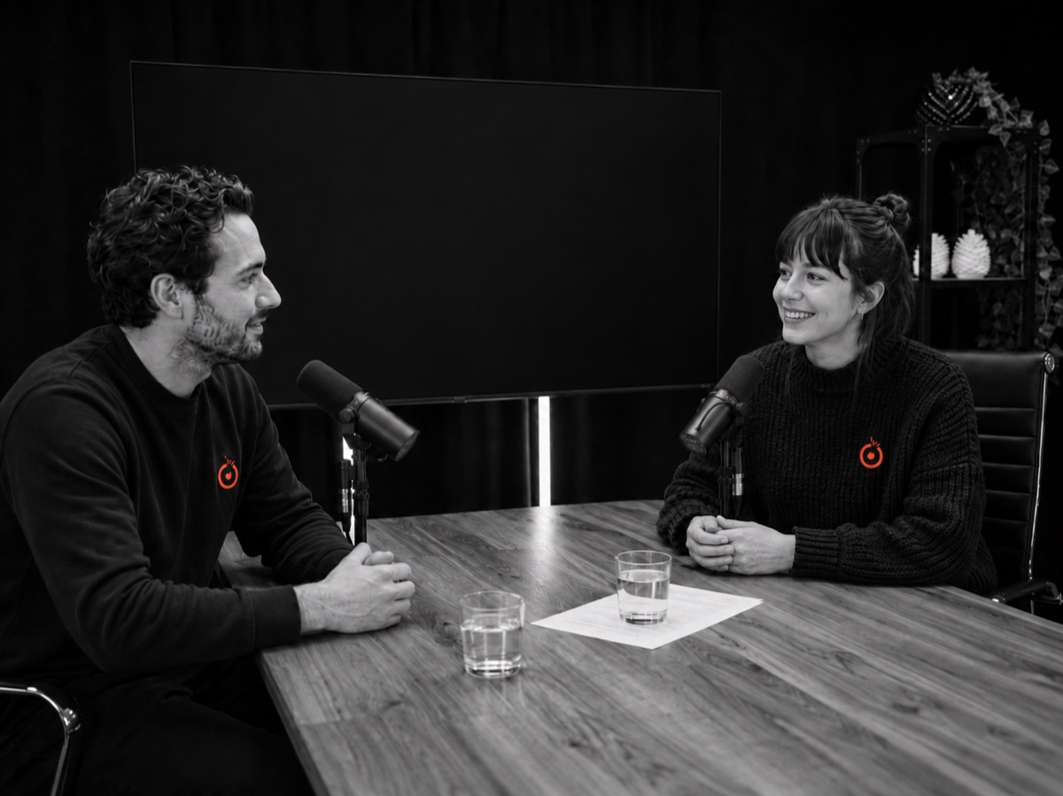 Deux personnes en entrevue au studio de GB Studio : micros, échange naturel, ambiance calme.